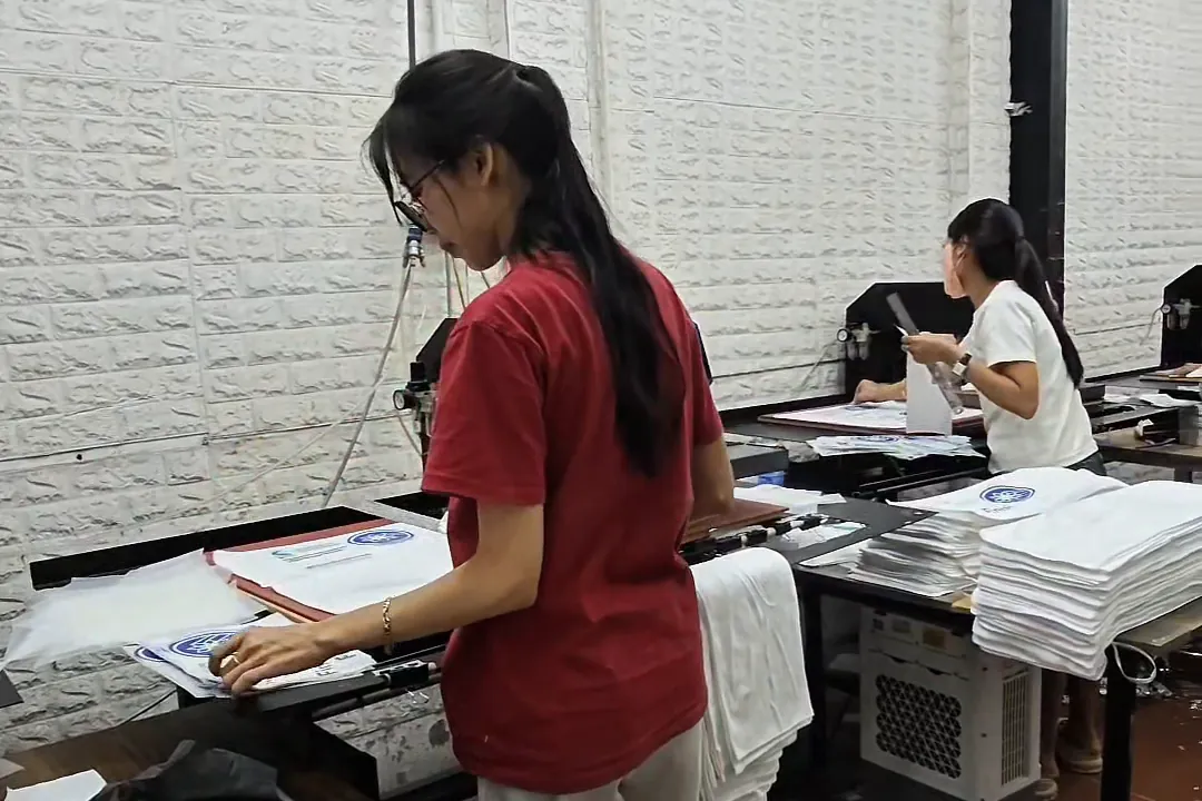 Nhân viên đặt sản phẩm và hình in PET lên bàn máy ép nhiệt