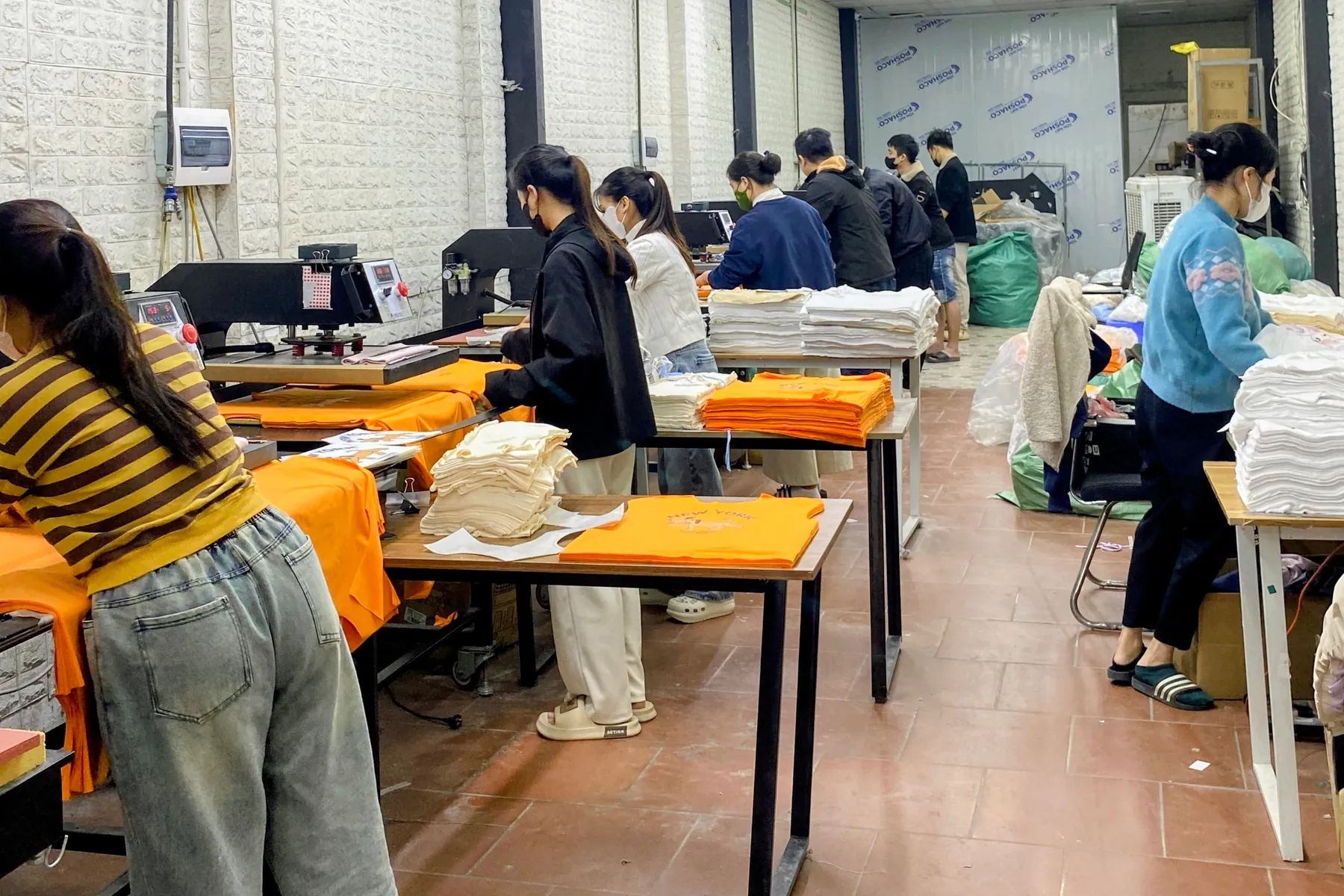 Nhân viên thao tác ép nhiệt hình in lên áo thun tại khu ép của xưởng